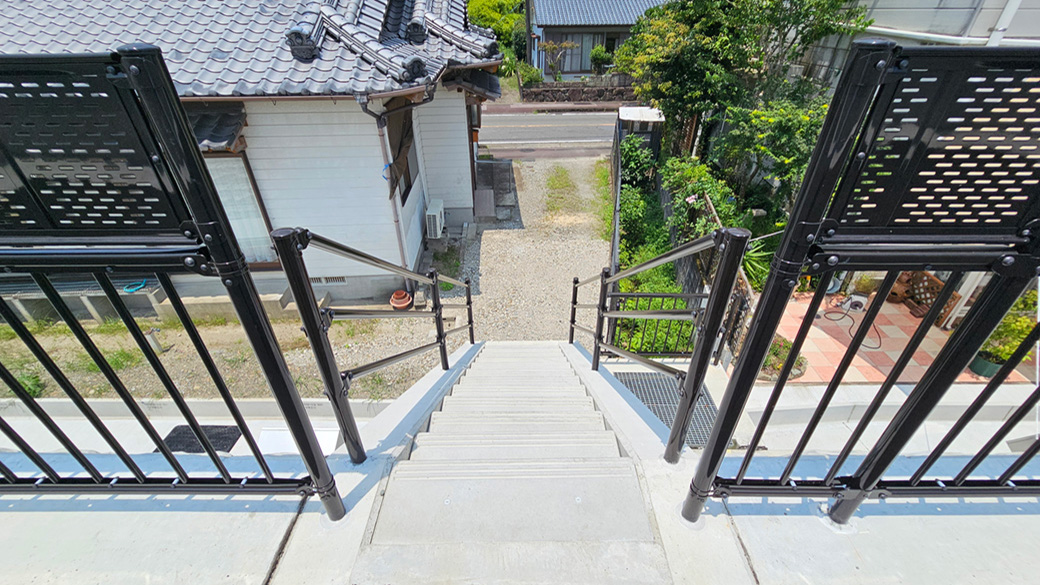 堤防側から見ると、階段から建物脇を通って県道へ続く動線がよく分かります。