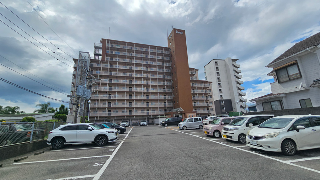 広々とした駐車場から望むマンション外観。