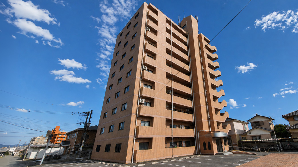 落ち着いた外観と平面駐車場。毎日の帰宅をイメージしやすい建物全景です。
